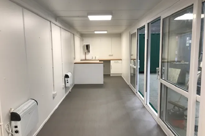 Modern container office interior with kitchenette, lighting, and full-height glazed windows – ideal for site offices or modular workspace solution