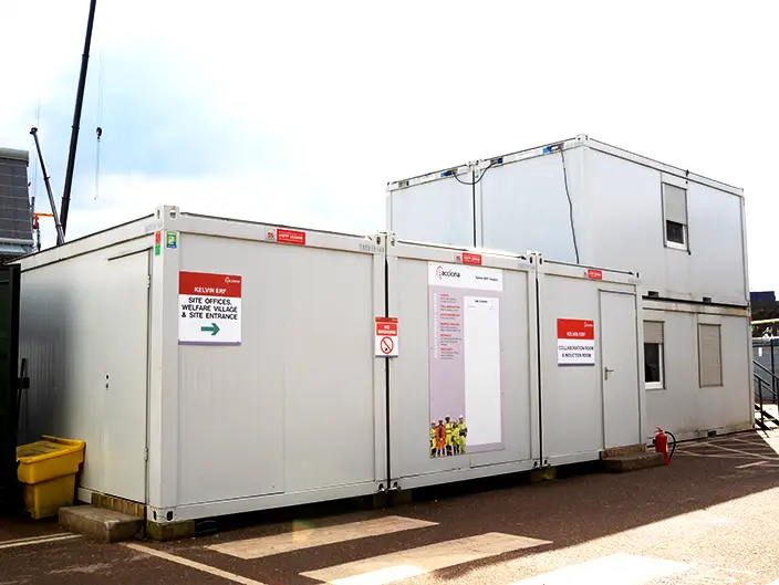 Exterior view of a single-story modular building on a construction site, with signage for site offices and welfare facilities
